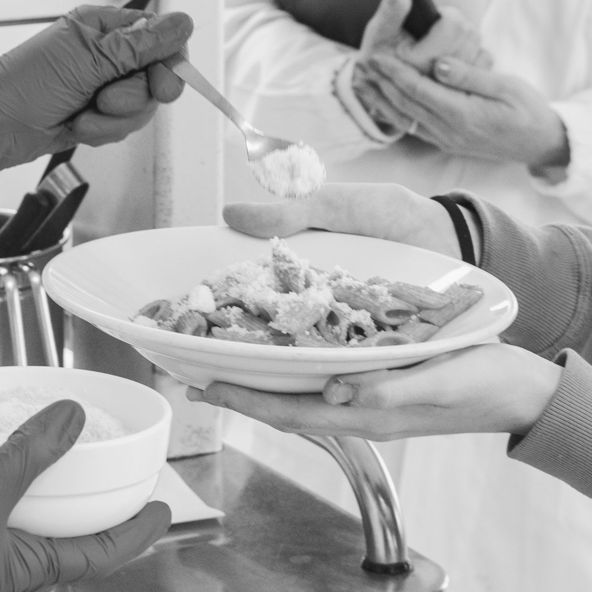 Mani che porgono un piatto durante il pasto